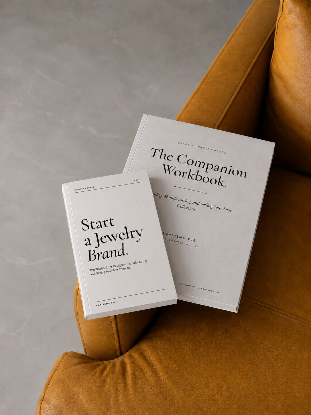 Start A Jewelry Brand book and The Companion Workbook resting on a mustard leather chair